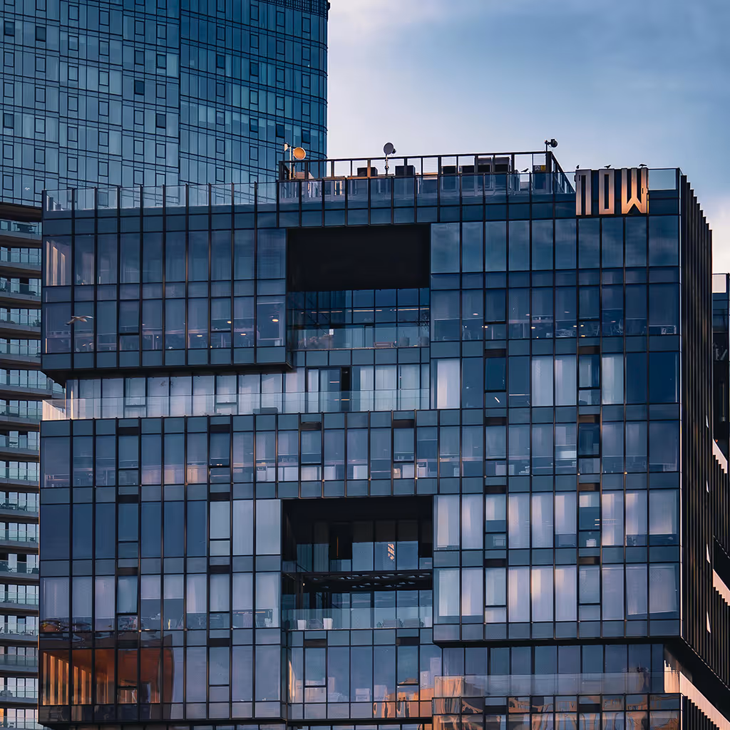 Modern high-rise building with reflective glass windows and geometric patterns during sunset.