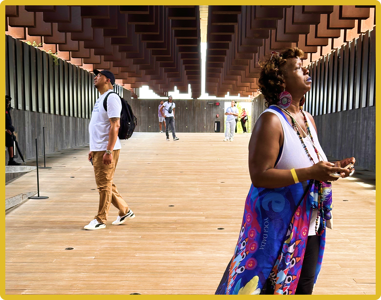 People observing hanging columns in an architectural space, wearing casual attire.