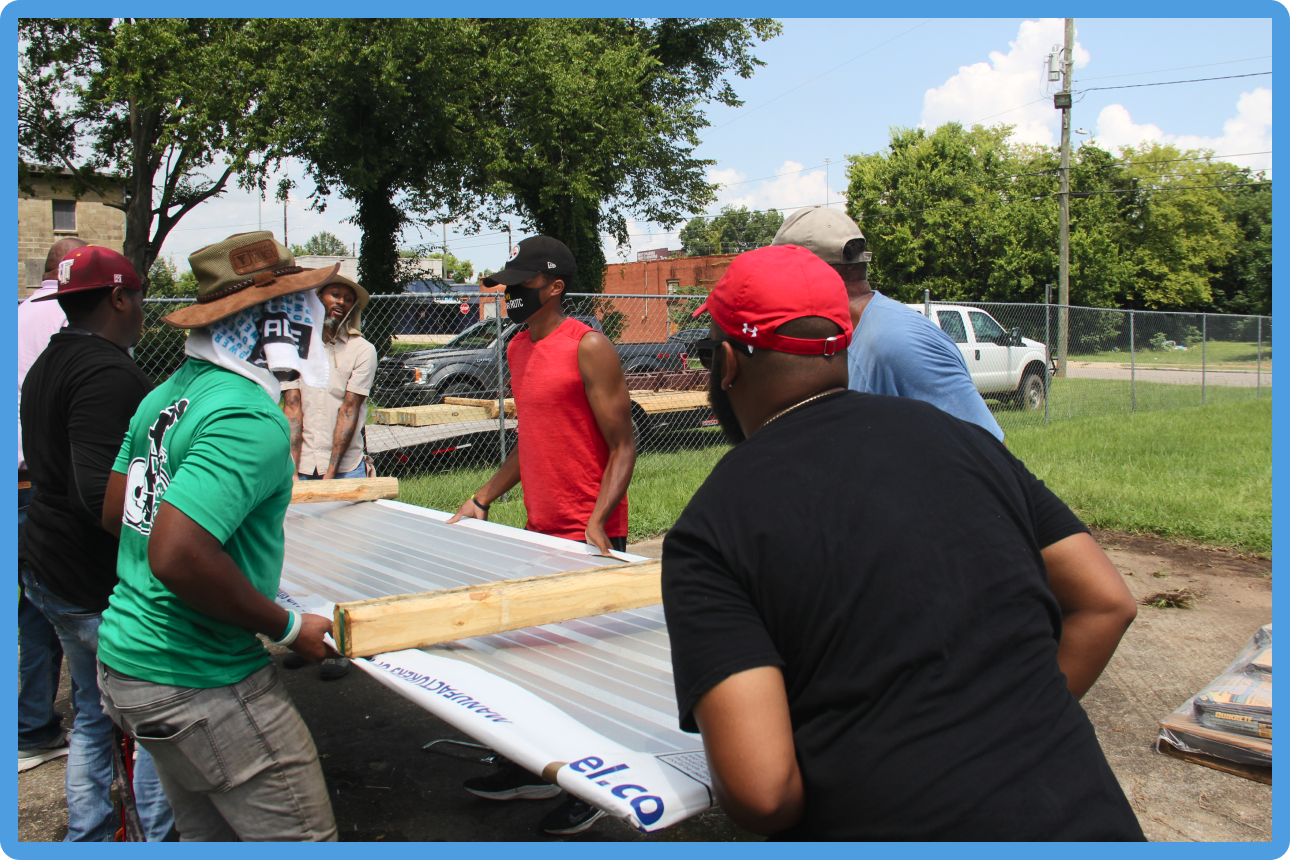 People working together outdoors, assembling materials under a clear sky.