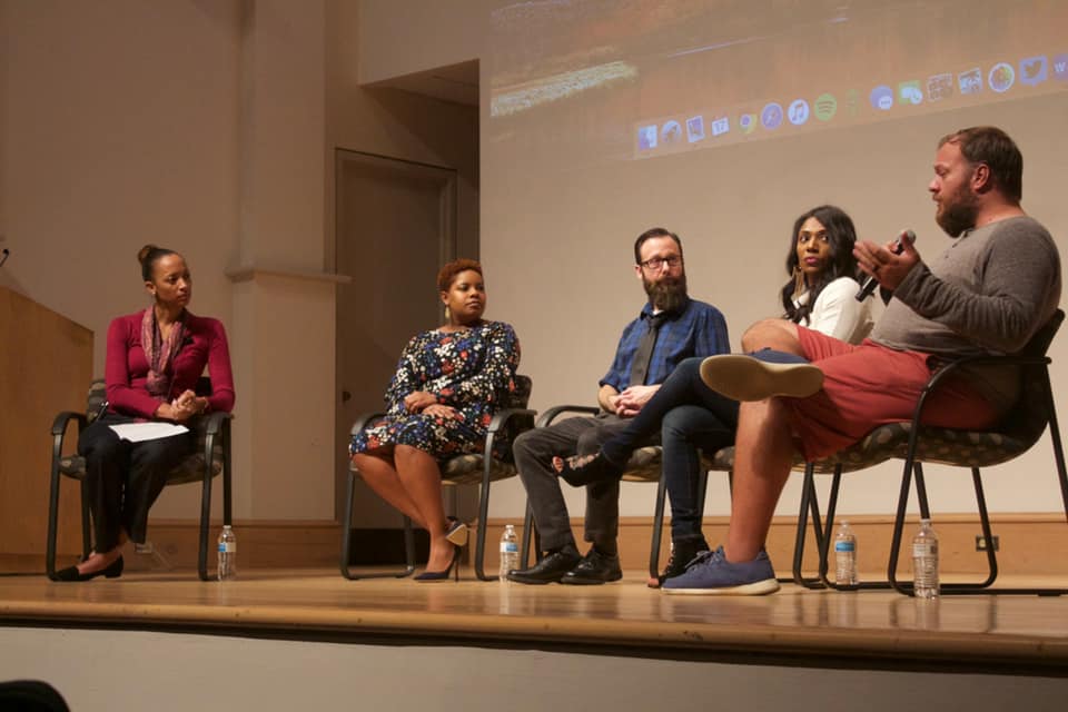 Panel discussion with five people seated on stage, engaging in conversation.