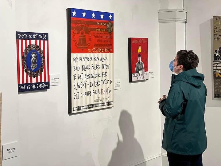Person viewing wall art in a gallery; includes text and graphic designs in frames.