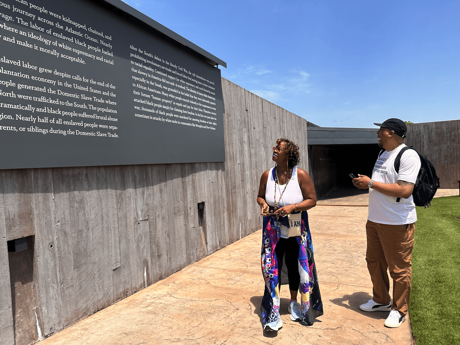 Smiling person holding colorful painting with pink ribbon, sitting at a table in an art class setting.