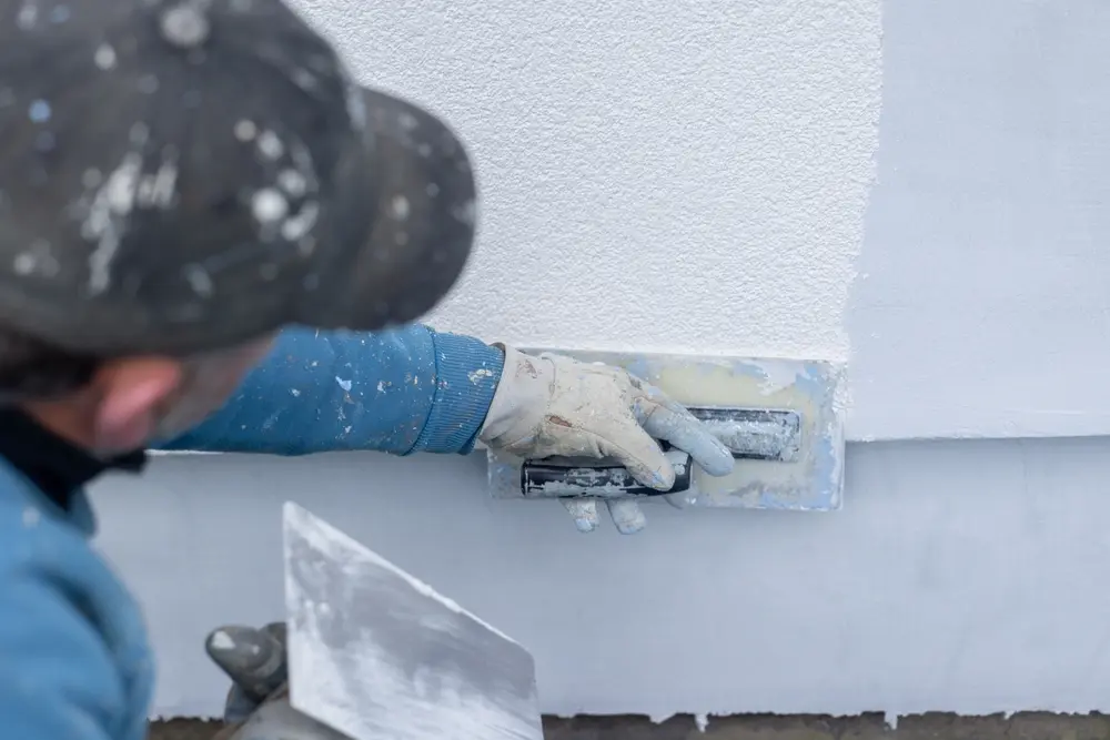 Worker applying stucco plaster on building