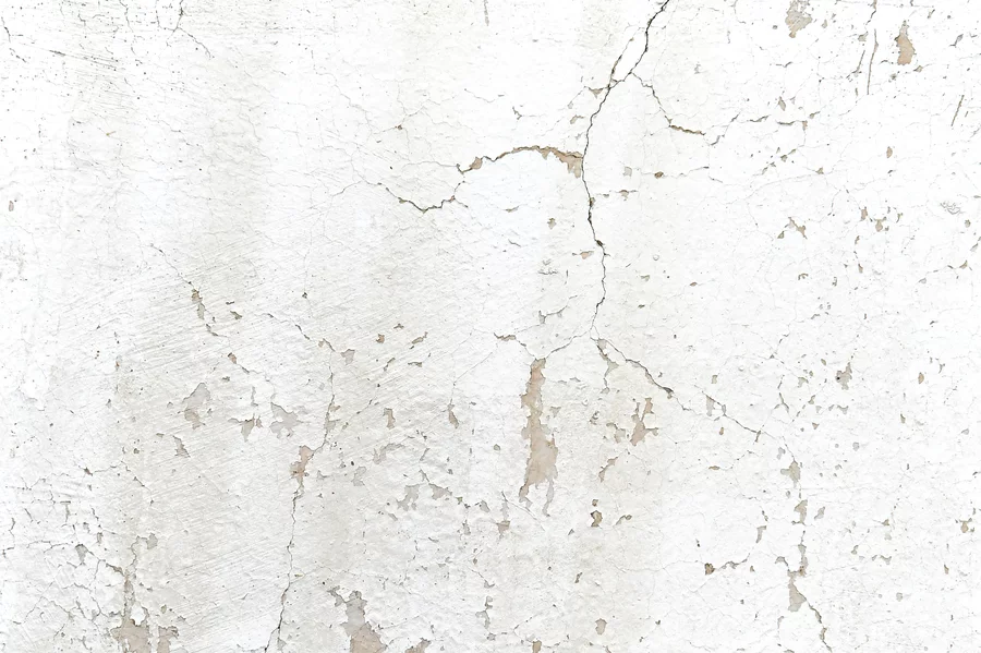 Cracking on an older white stucco wall