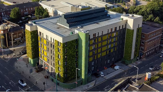 The Mailbox accommodation building with green living wall surrounded by urban cityscape
