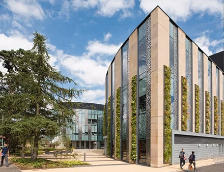 University of Edinburgh building with living wall and green trees under blue sky