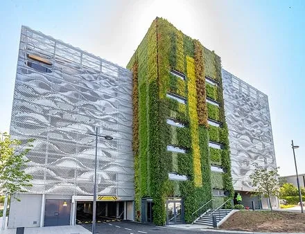 Modern building with living green wall and metallic facade on sunny day