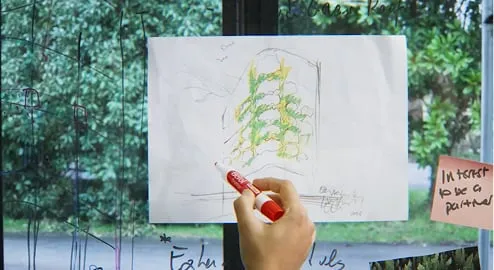 Living wall sketch with green vines drawn on white paper near window