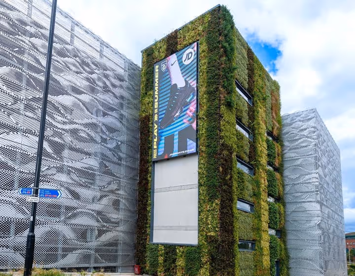 Living wall covers modern building with green vegetation and digital display