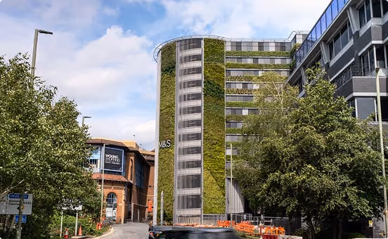 Living wall on modern cylindrical building with green vegetation and urban trees