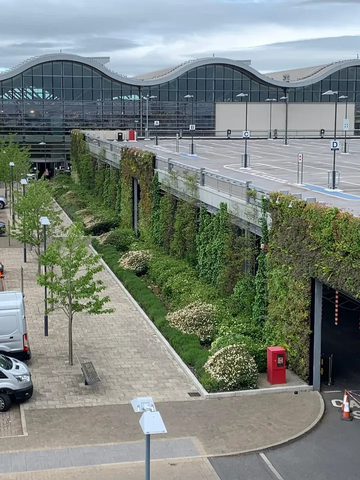 Living wall along parking area near modern curved building with landscaping