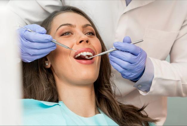 photo of a young female patient getting her teeth examined by a dentist