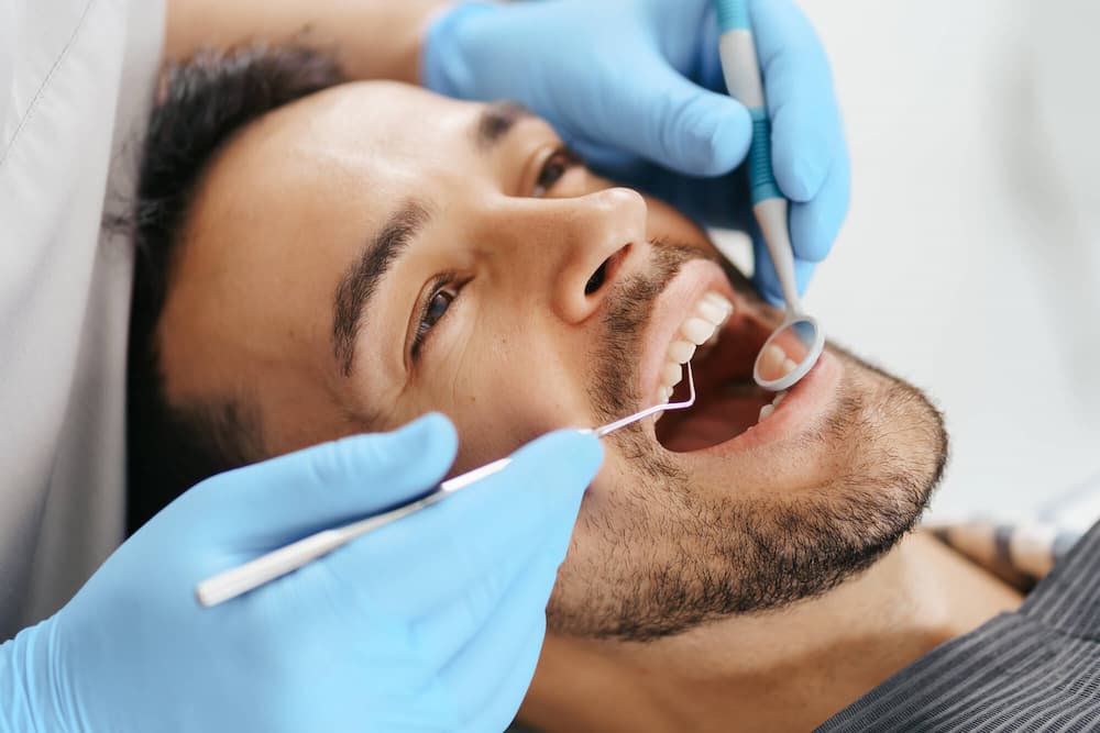 photo of a young man getting his teeth examined by a dentist
