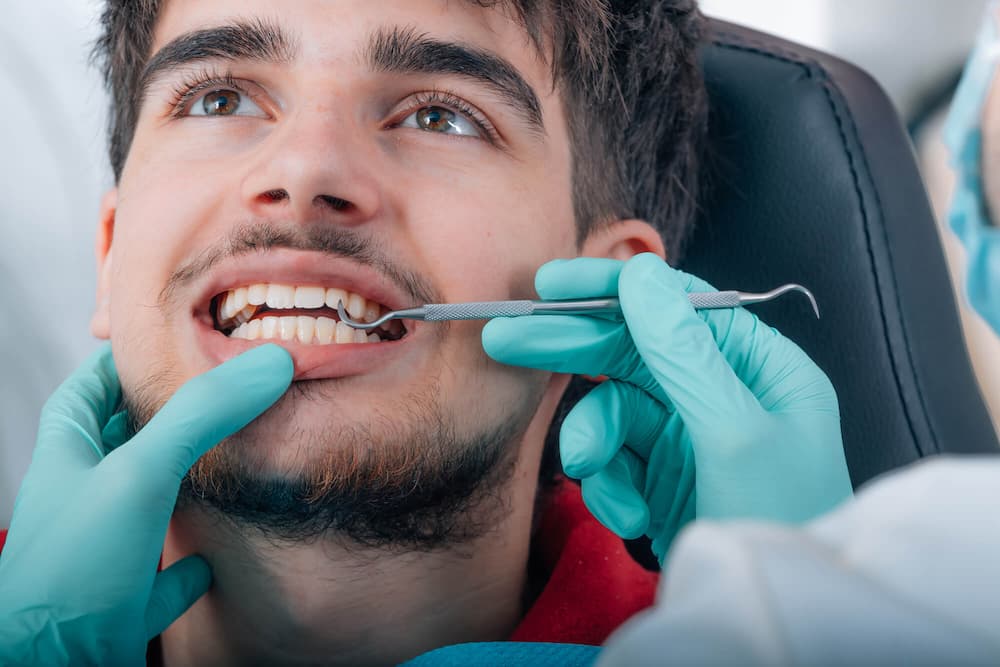 close-up of a young man having his teeth examined by a dentist