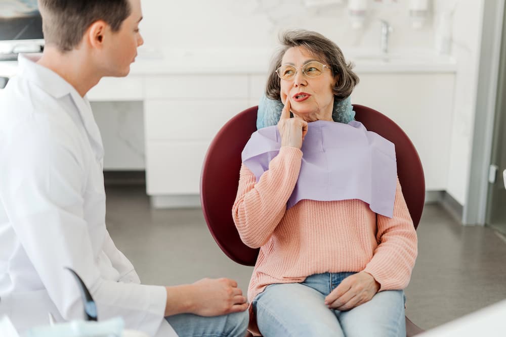 photo of an older female patient  talking to the dentist about her dental concern