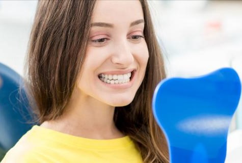 photo of a female patient looking in the mirror and checking her teeth