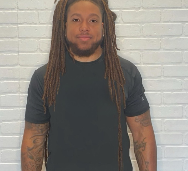 A photo of Ja’Tyuan smiling, wearing a black t-shirt