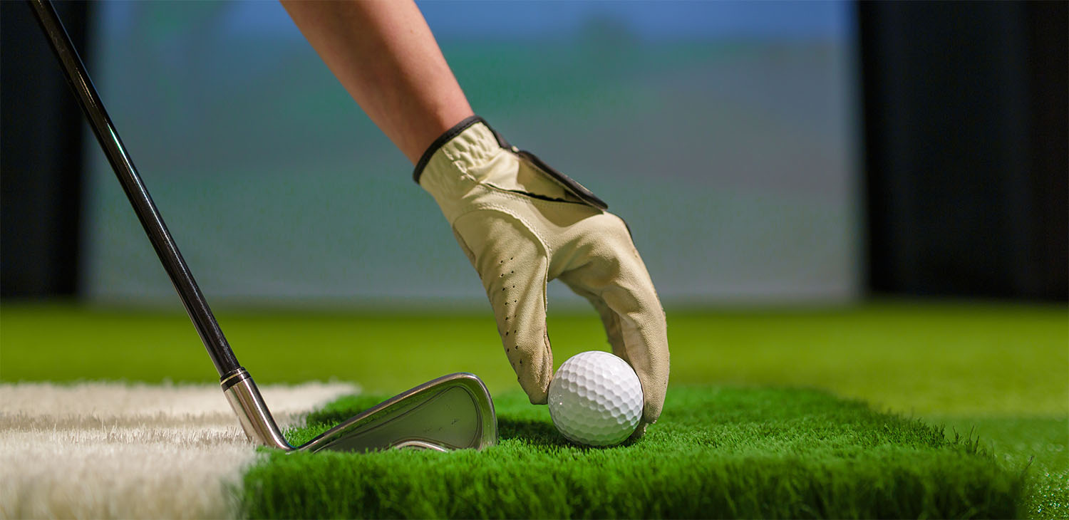 golfer placing a golf ball on grass