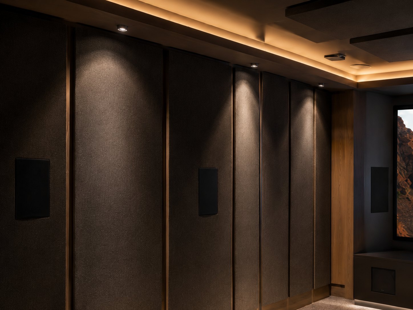 Fabric-wrapped acoustic panels on the side walls of a finished home theatre, showing first-reflection control integrated into the wall lining and interior design.