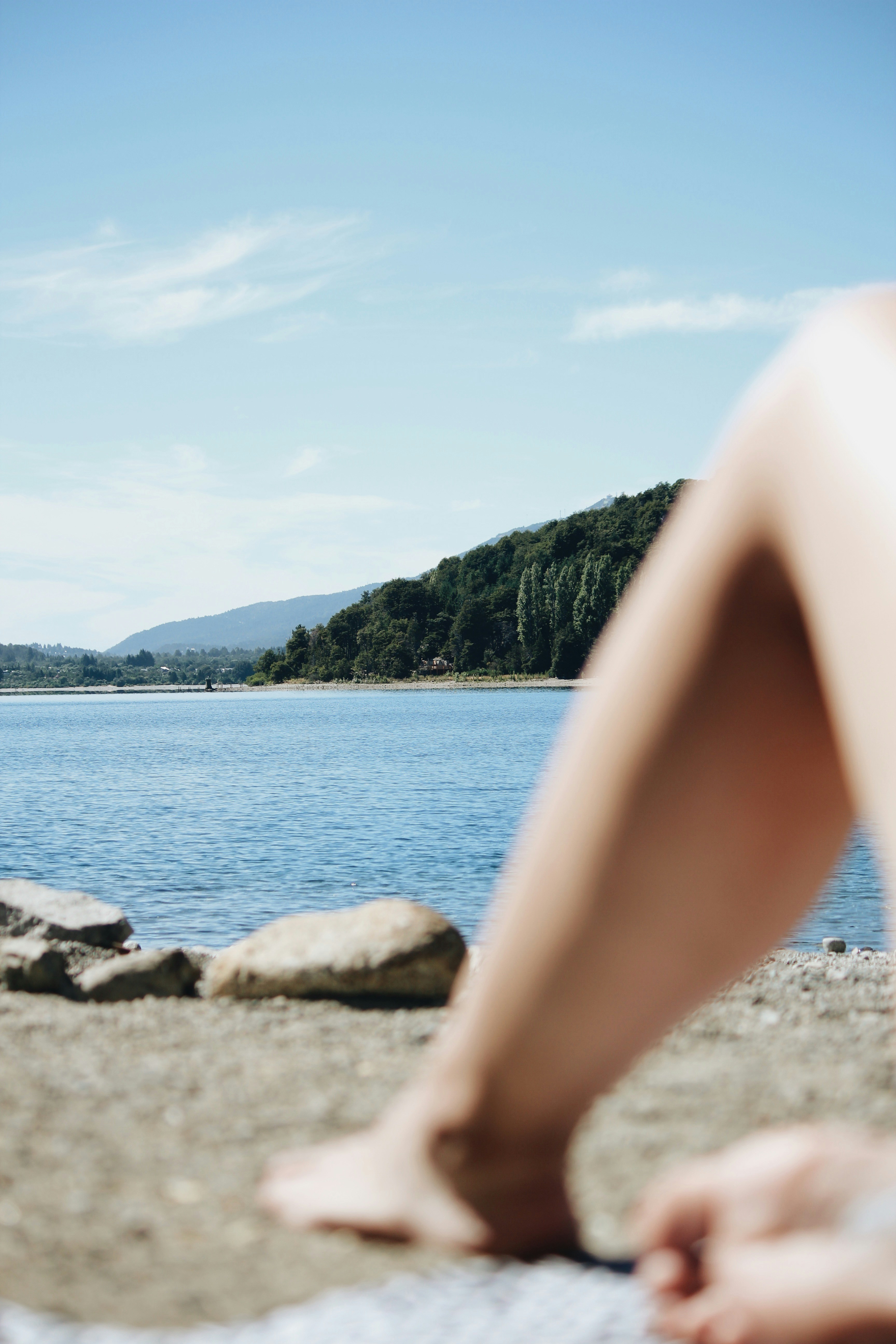 The view of a lake with the person's leg in the foreground