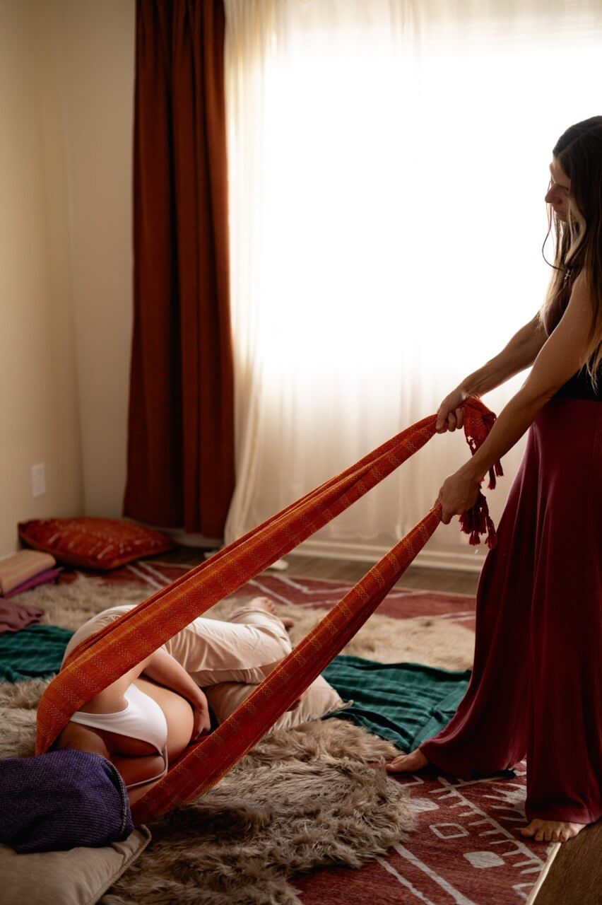 Practitioner guiding a rebozo session with a red woven cloth
