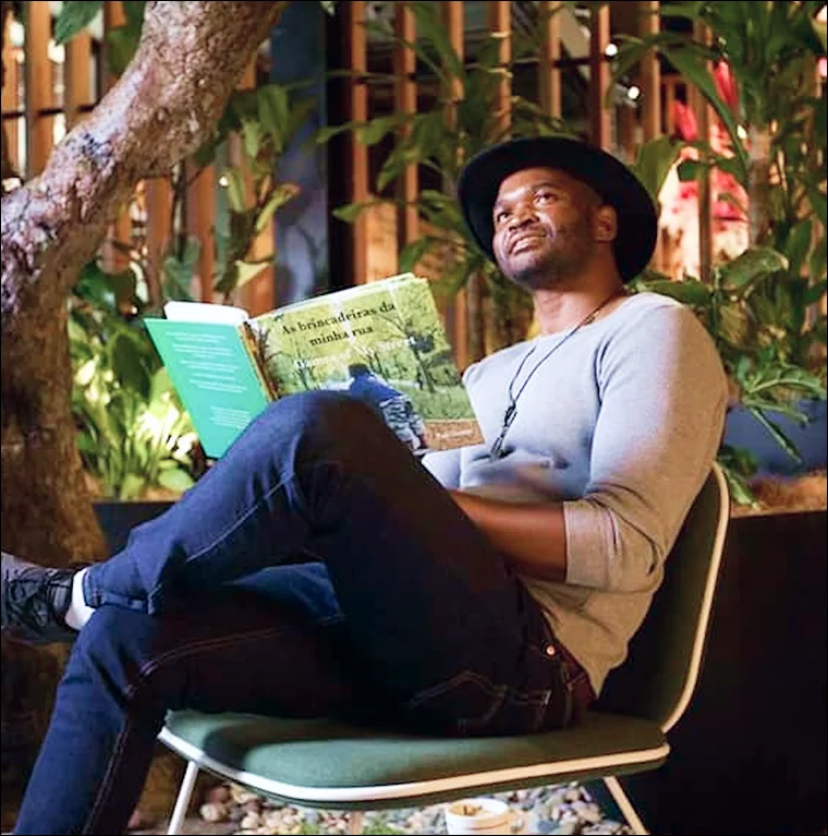 Paulo sitting while holding his book 