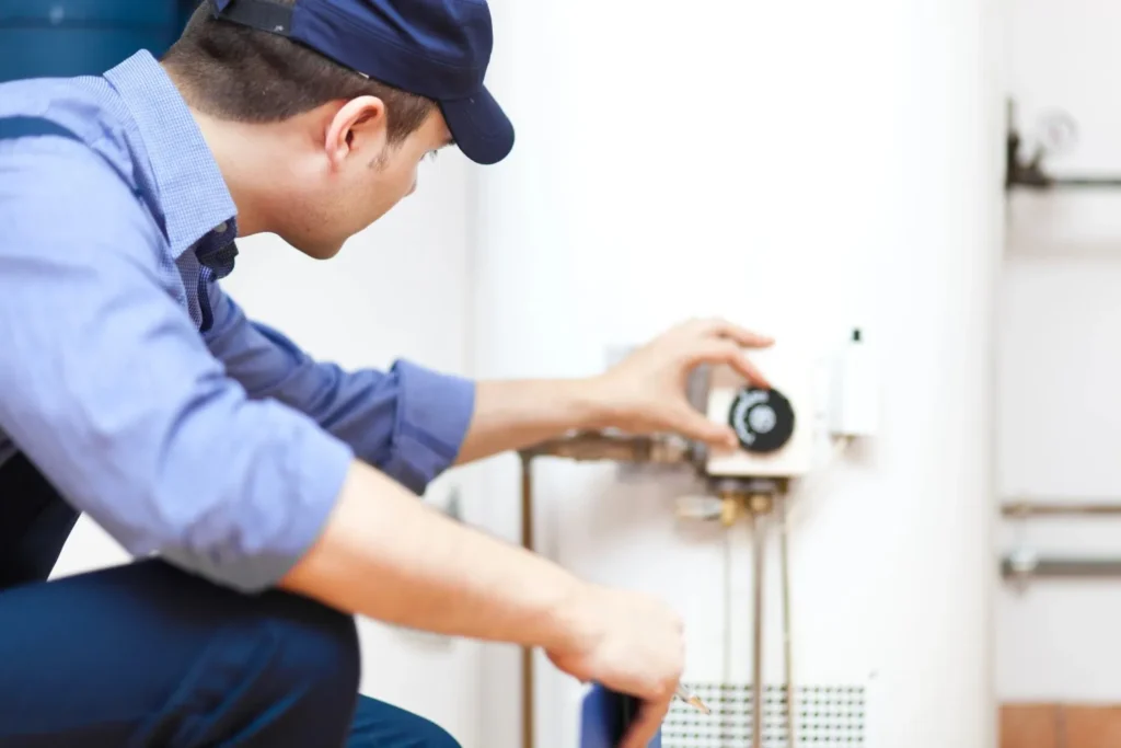 A technician wearing a proper gears and cap is maintaining a boiler
