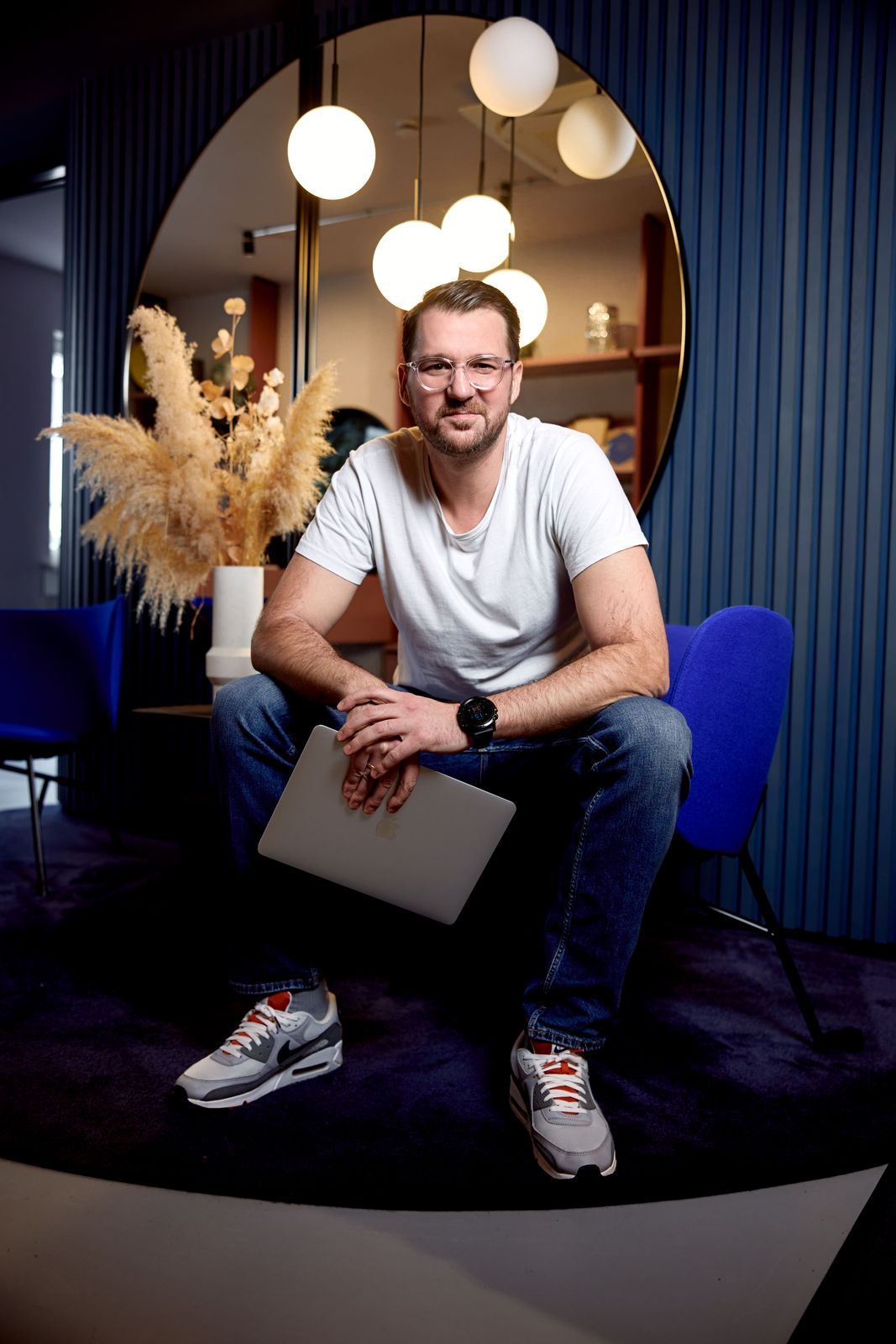 Philip Fuchslocher sitzt in einem blauen Sessel und lächelt direkt in die Kamera