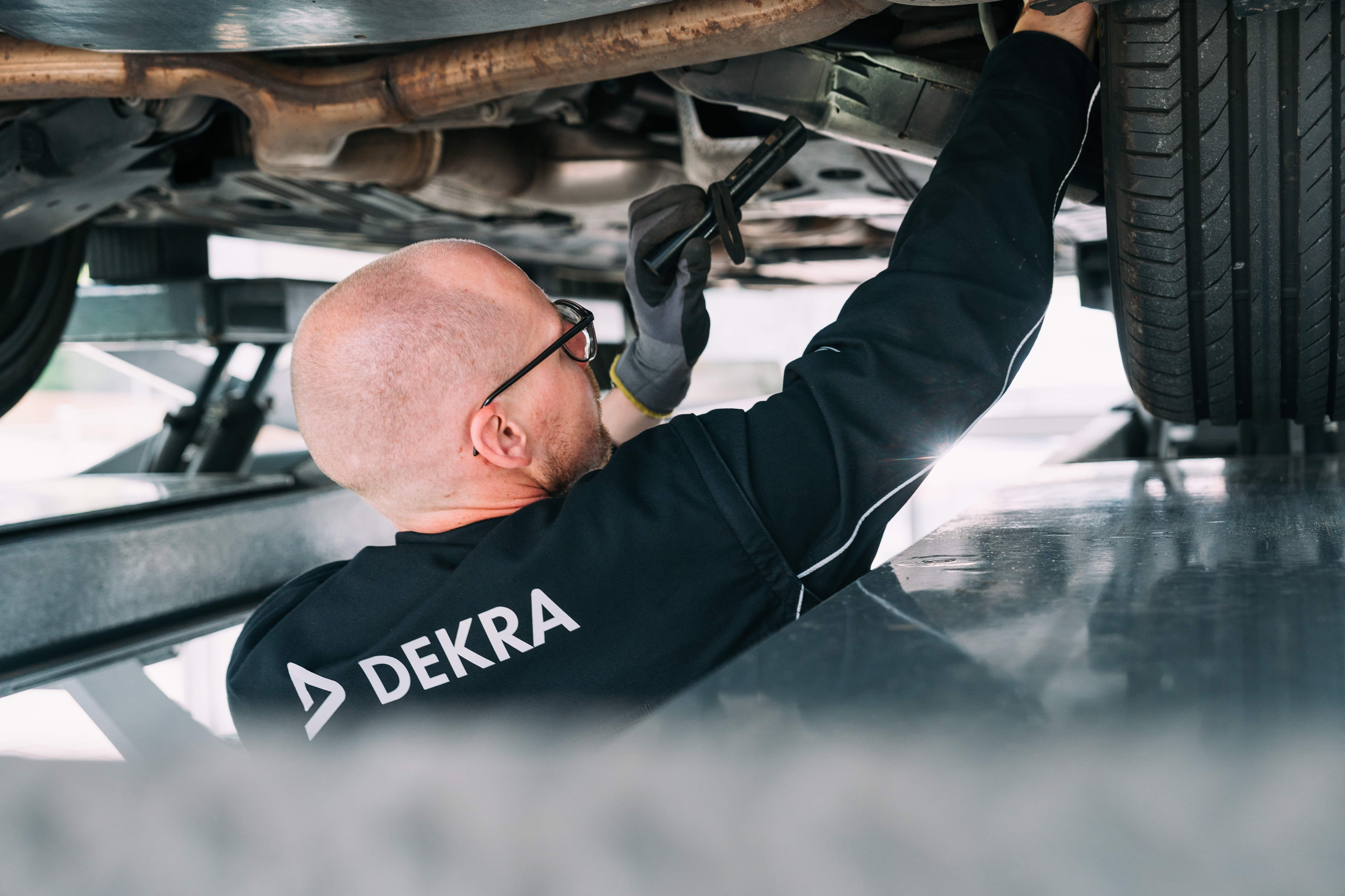 DEKRA-Prüfer kontrolliert die Fahrzeugunterseite bei der Hauptuntersuchung