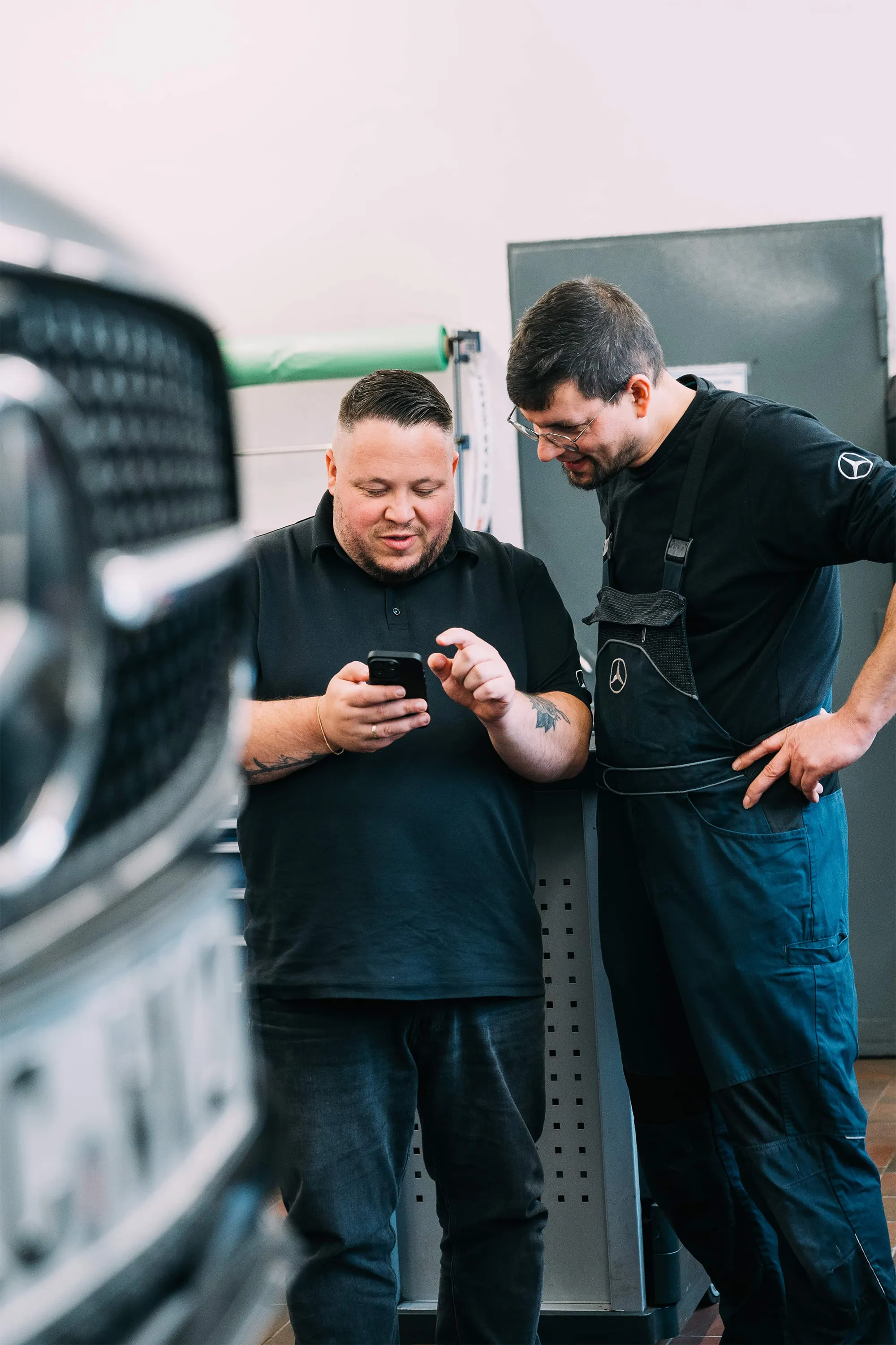 Zwei Mitarbeiter von Autohaus Meyer schauen gemeinsam auf ein Smartphone