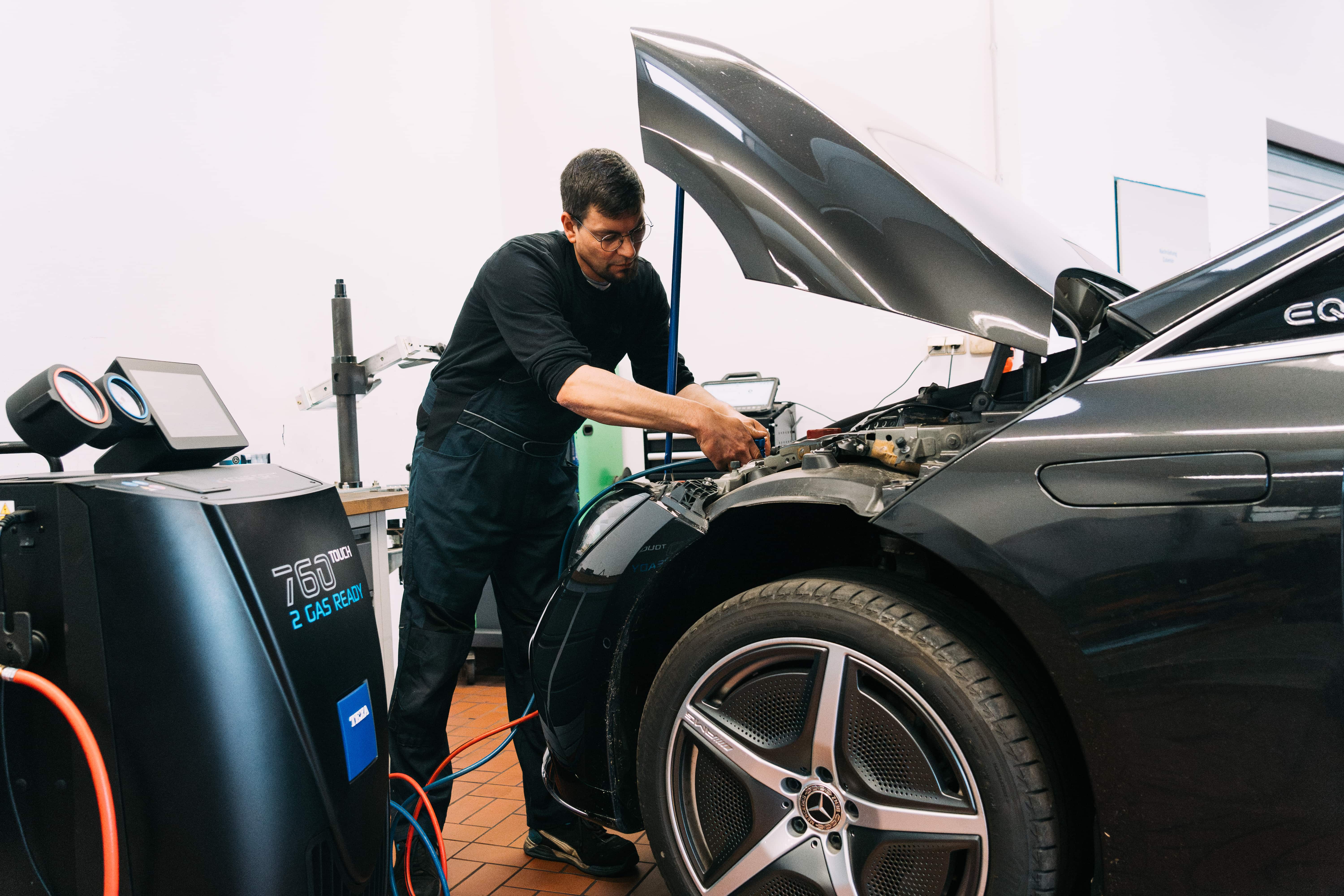 Mechaniker wartet die Klimaanlage eines Mercedes-Benz mit einem Klimaservicegerät