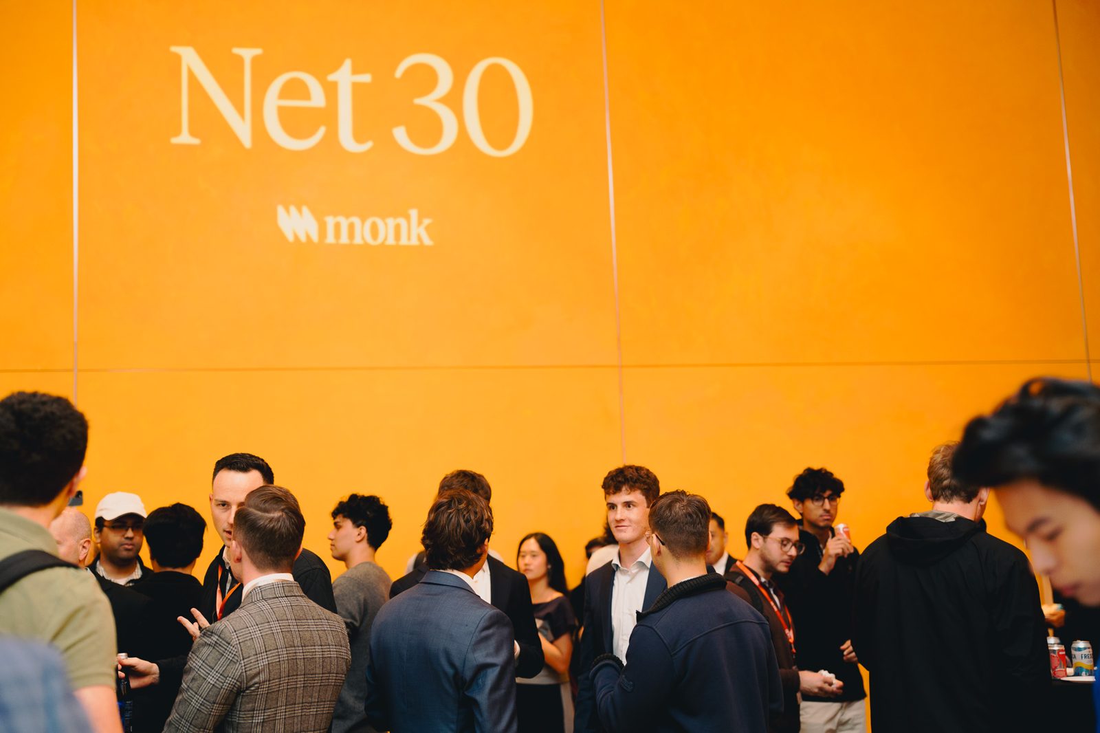 Guests networking in front of the Net 30 wall