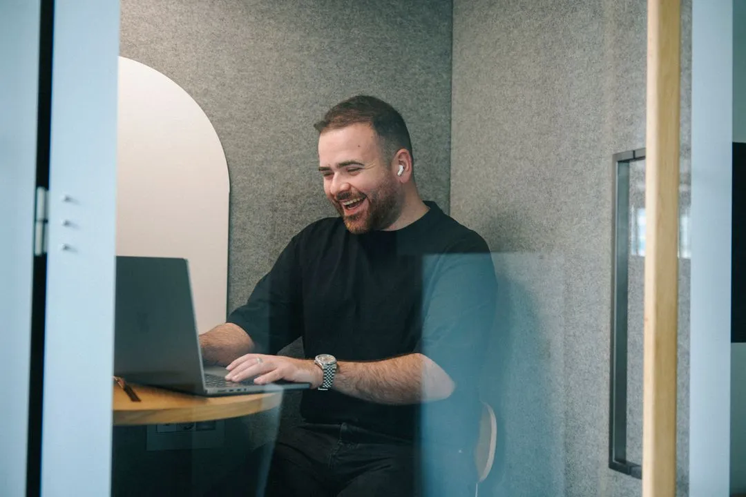 Ein junger Mann in einer Call-Box am Laptop