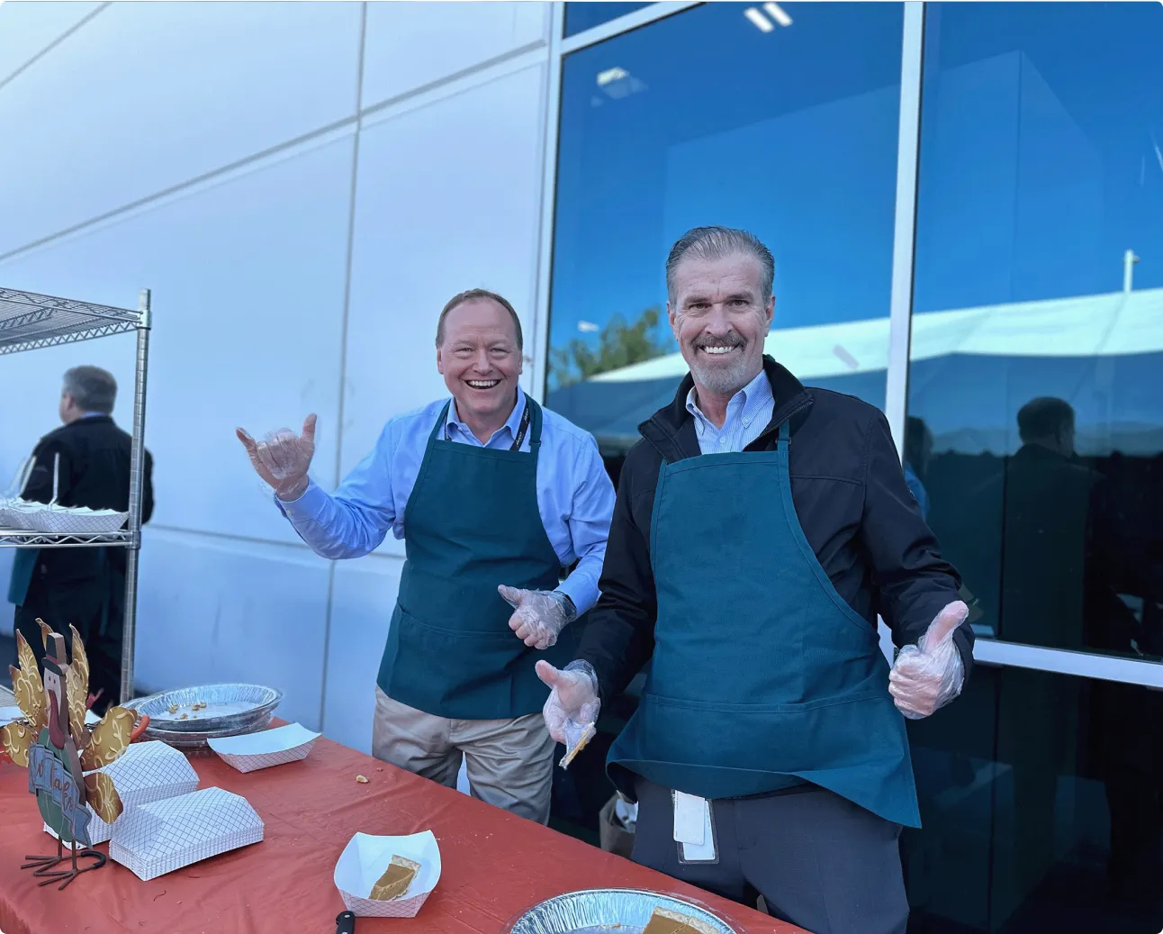 A couple of men standing next to each other near a table.