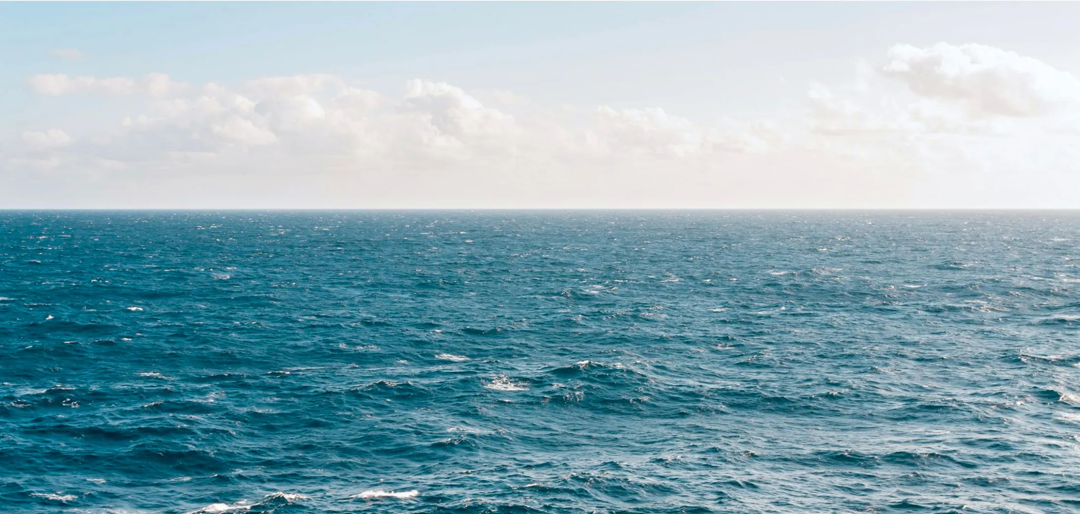 A large body of water with some clouds in the sky.