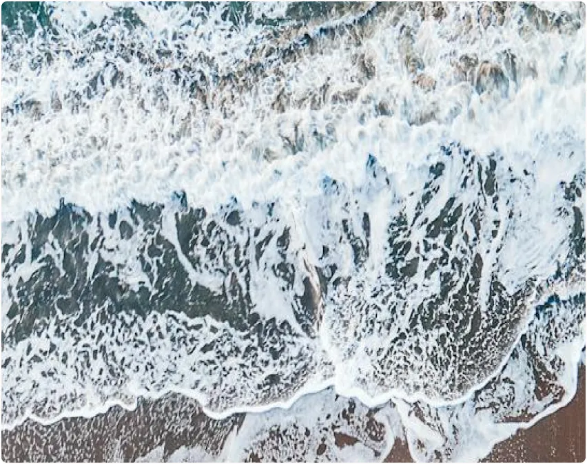 An aerial view of the ocean waves and sand.