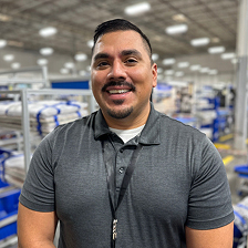 A man in a gray shirt is smiling.
