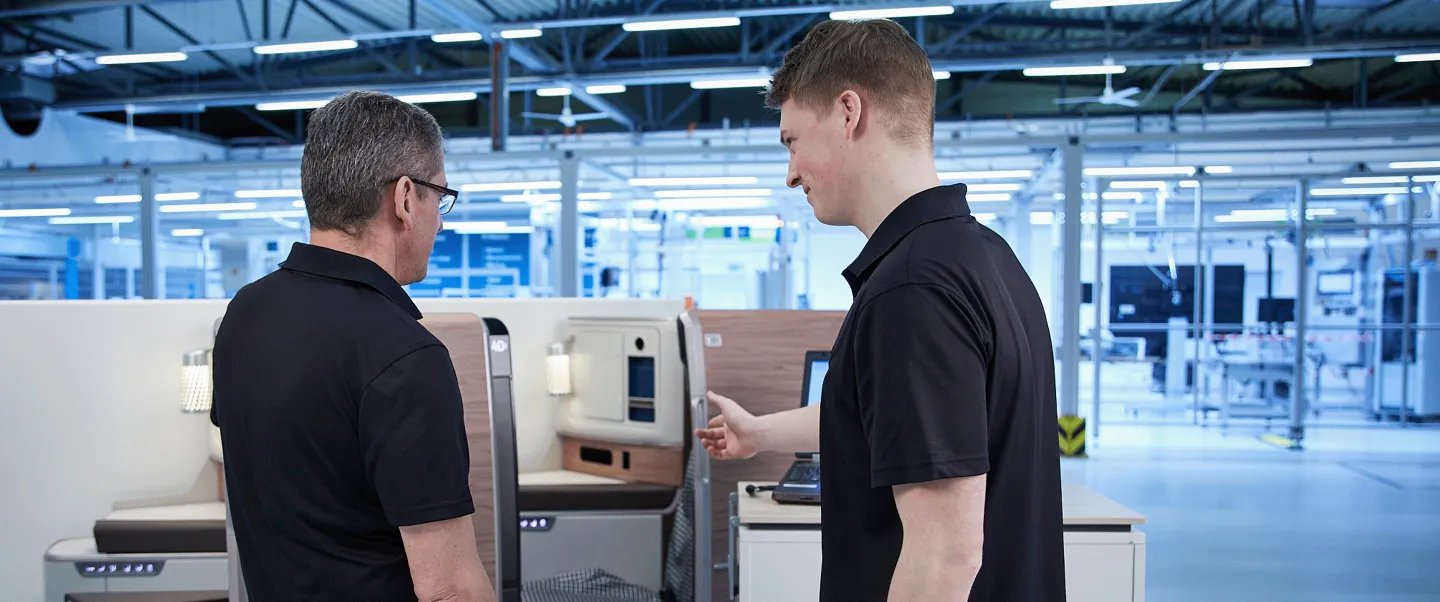 Two men standing in front of a machine in a factory.