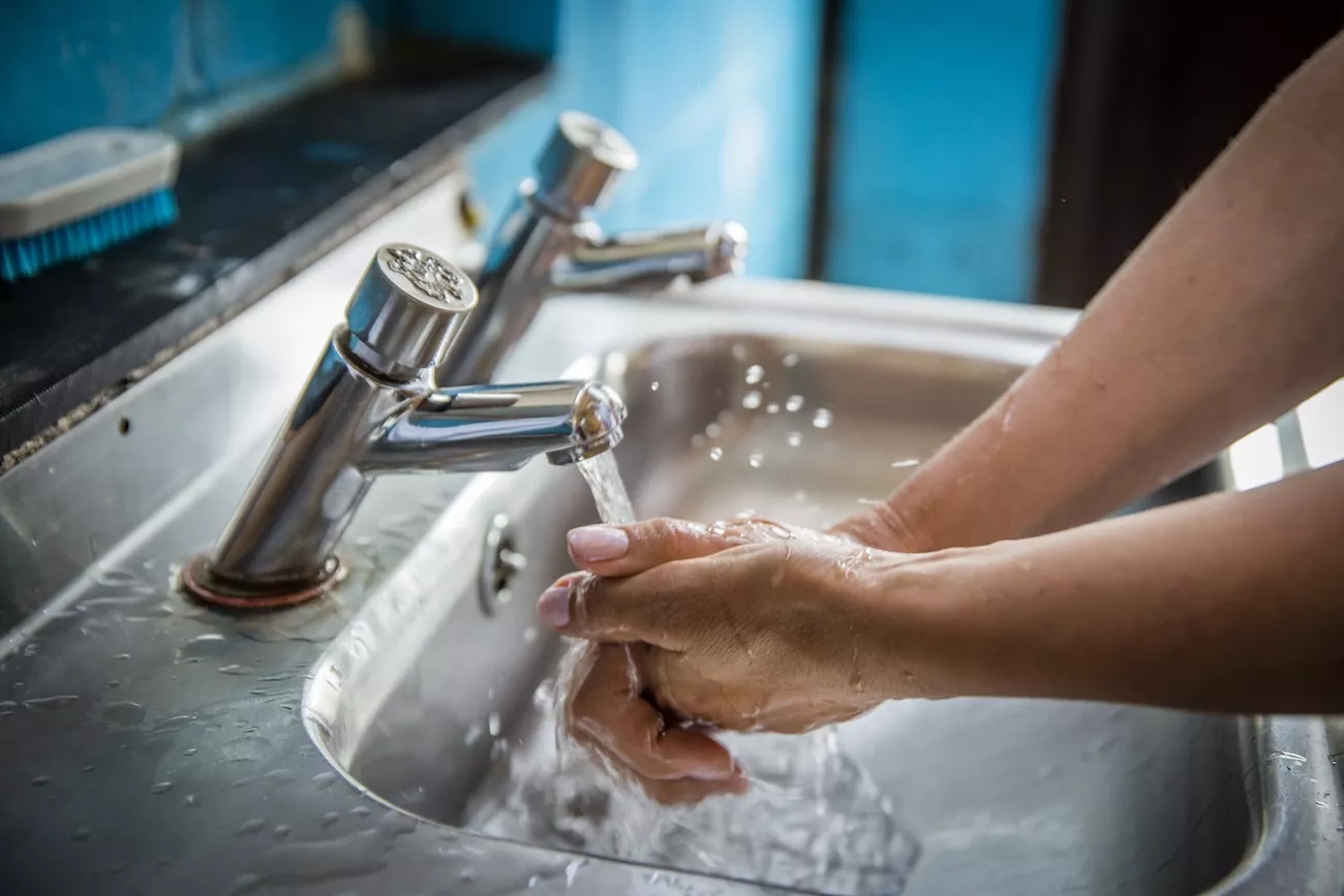 Person washing their hands in a sink.