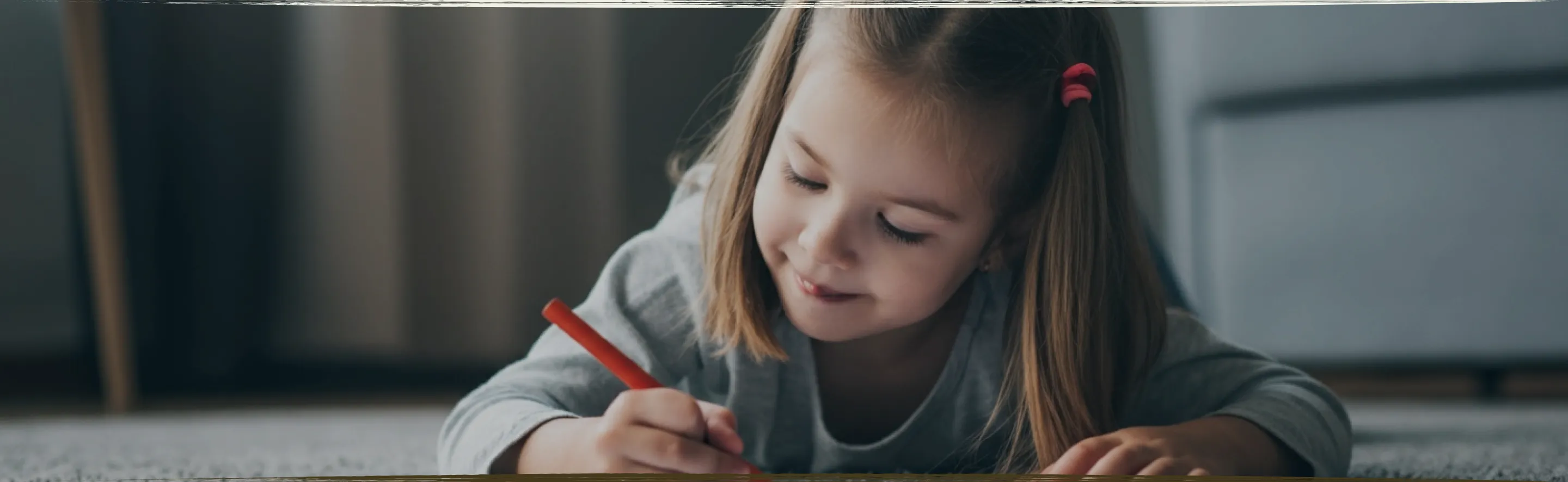 A young child lying on the floor focused on arranging colorful therapeutic stickers, demonstrating concentrated play-based learning activities