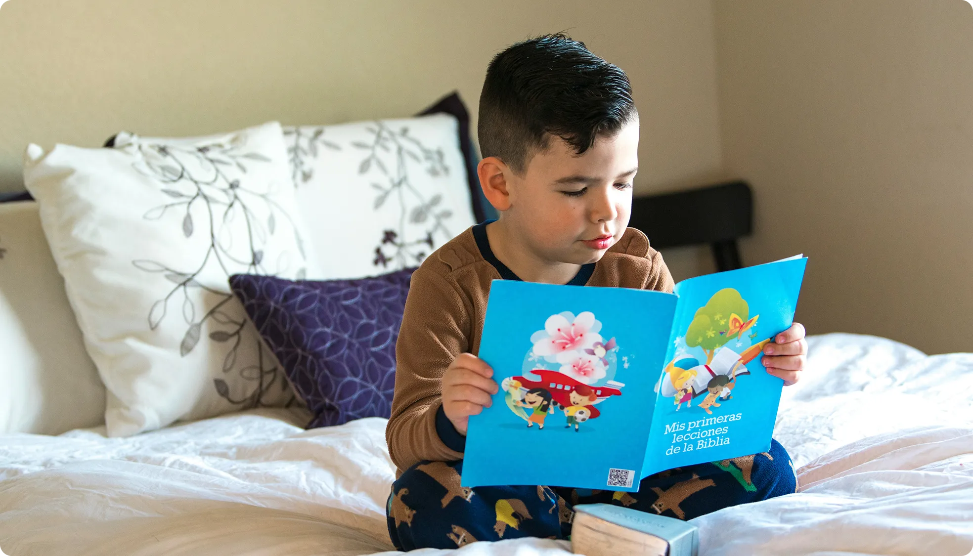 a boy reading a book on a bed
