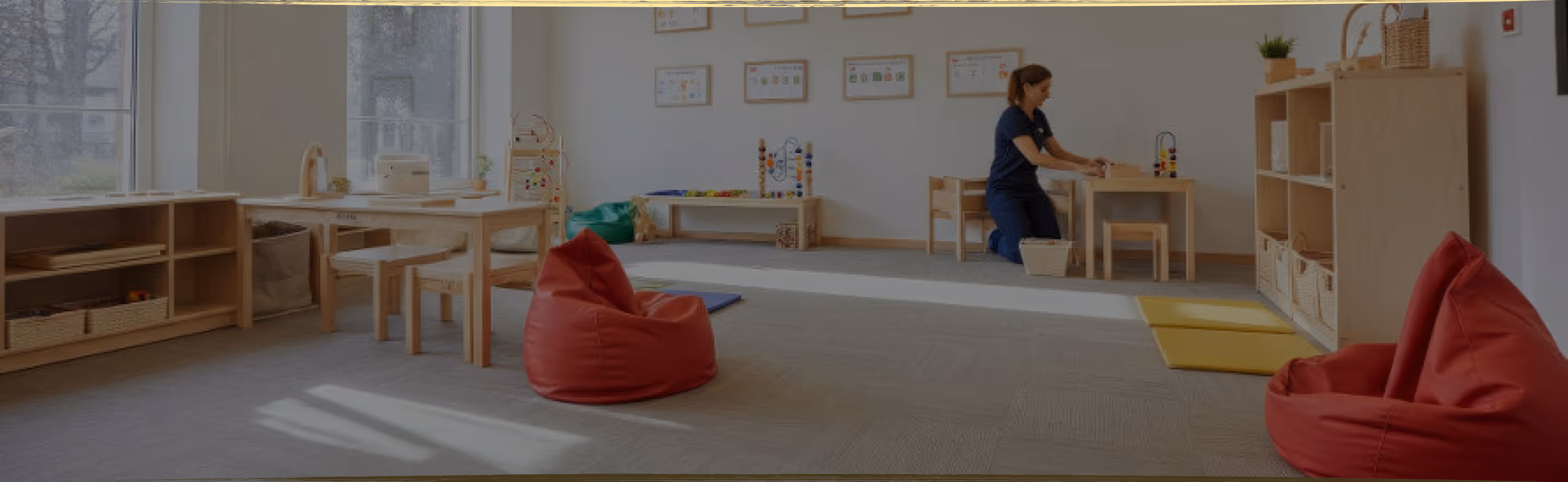 A young child lying on the floor focused on arranging colorful therapeutic stickers, demonstrating concentrated play-based learning activities
