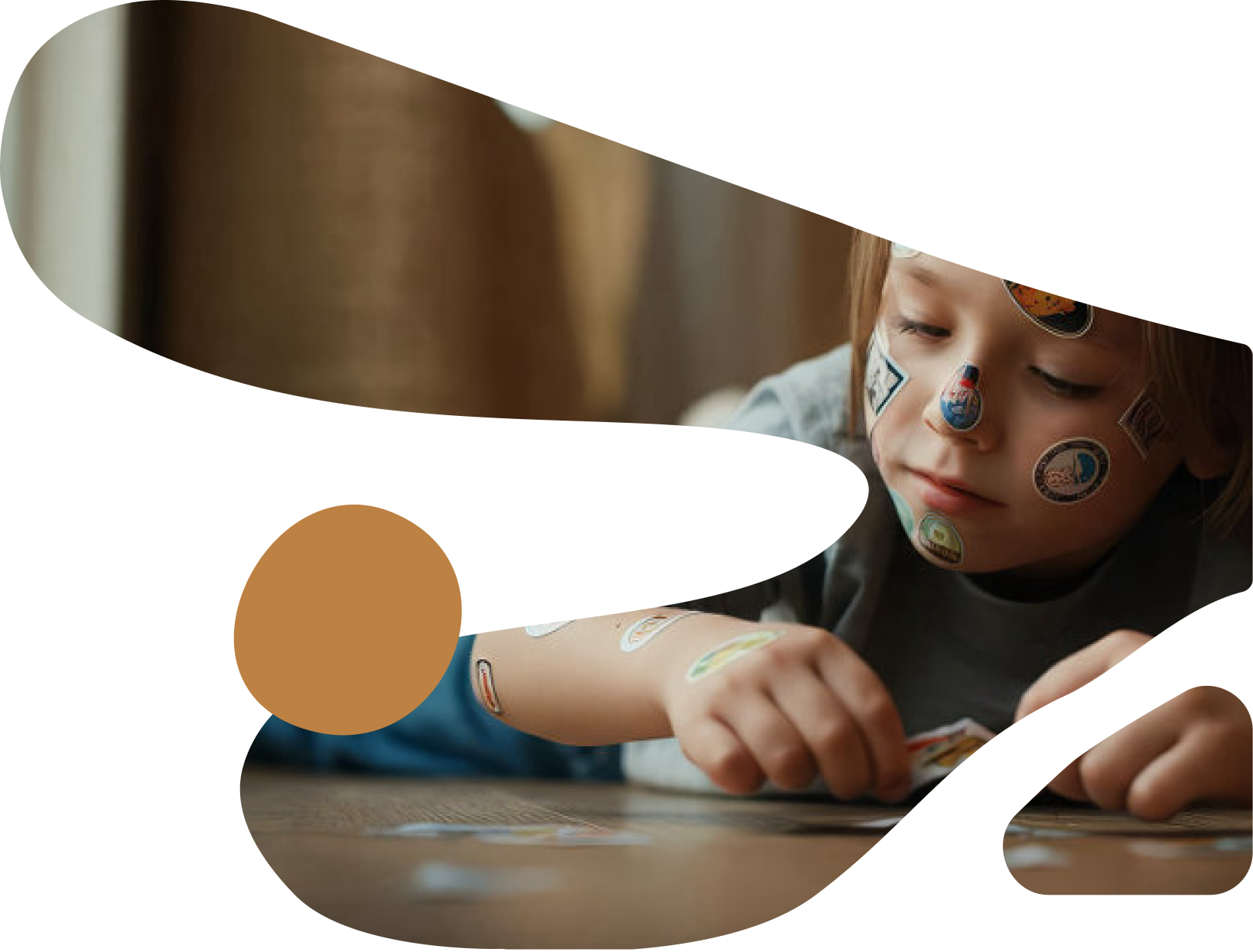 A father watching his young son play at a colorful outdoor playground structure with a spaceship design, both wearing matching blue shirts in a warm, natural setting