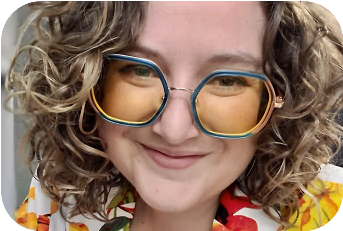 Portrait of Jennifer Head, with curly blonde hair, wearing large round glasses and a colorful shirt. The card highlights the badge “Mentor and trainer” and describes her leadership with empathy and evidence-based strategies.