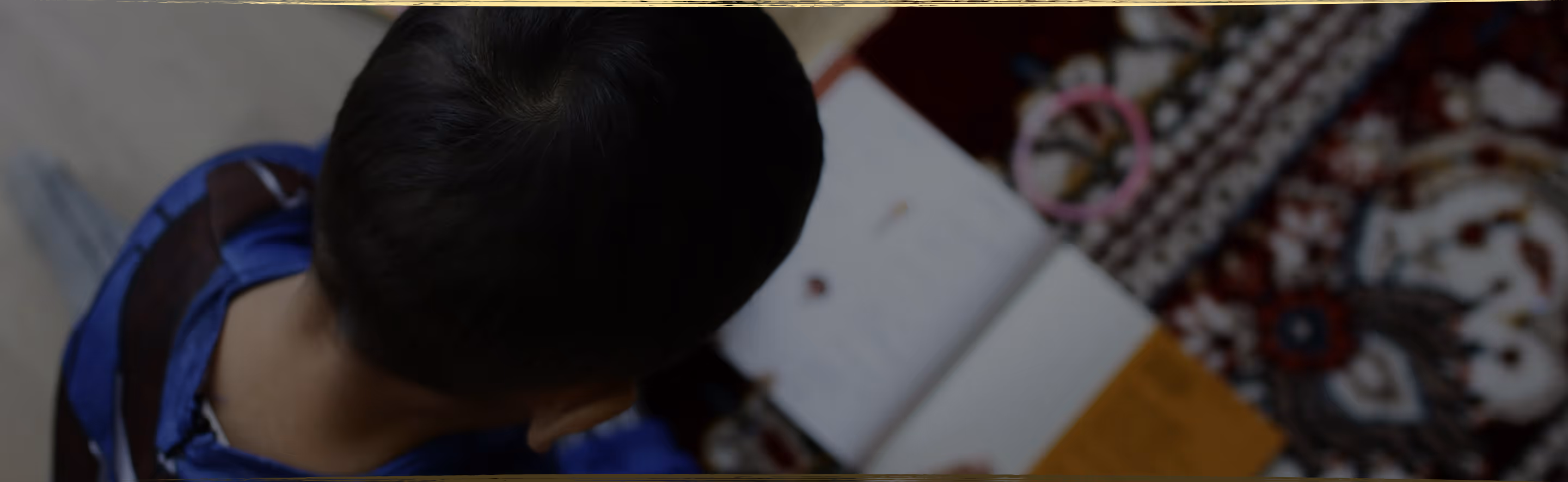 A young child lying on the floor focused on arranging colorful therapeutic stickers, demonstrating concentrated play-based learning activities