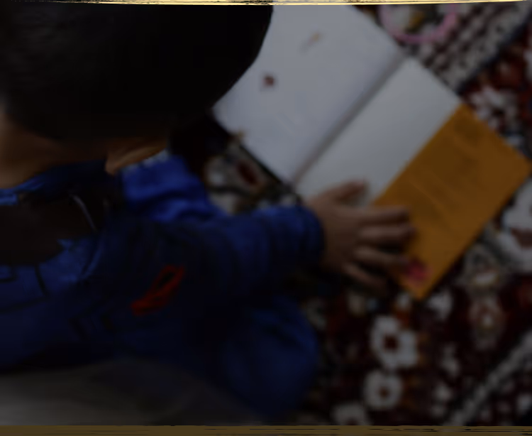 A young child lying on the floor focused on arranging colorful therapeutic stickers, demonstrating concentrated play-based learning activities