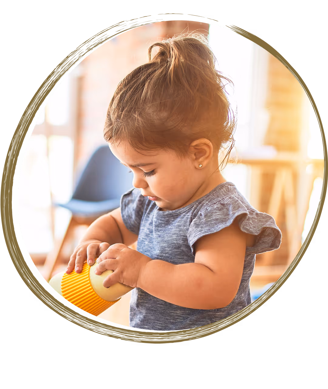 Toddler holding and examining a yellow toy cup, focusing on sensory play and motor skills development.