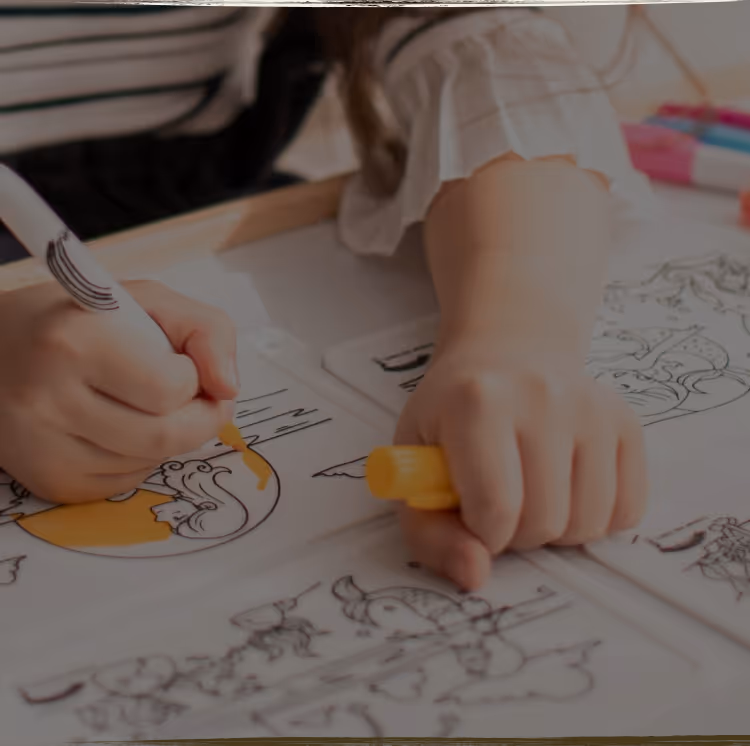 A young child lying on the floor focused on arranging colorful therapeutic stickers, demonstrating concentrated play-based learning activities
