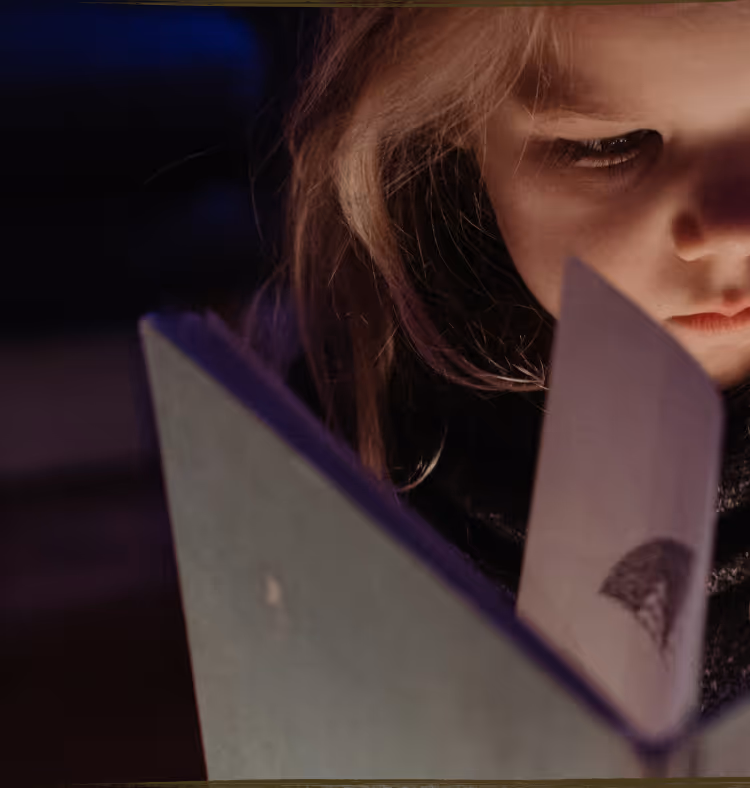 A young child lying on the floor focused on arranging colorful therapeutic stickers, demonstrating concentrated play-based learning activities