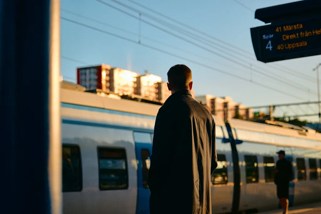 Person väntar på tåg vid Flemingsberg pendeltågstation i morgonljus.